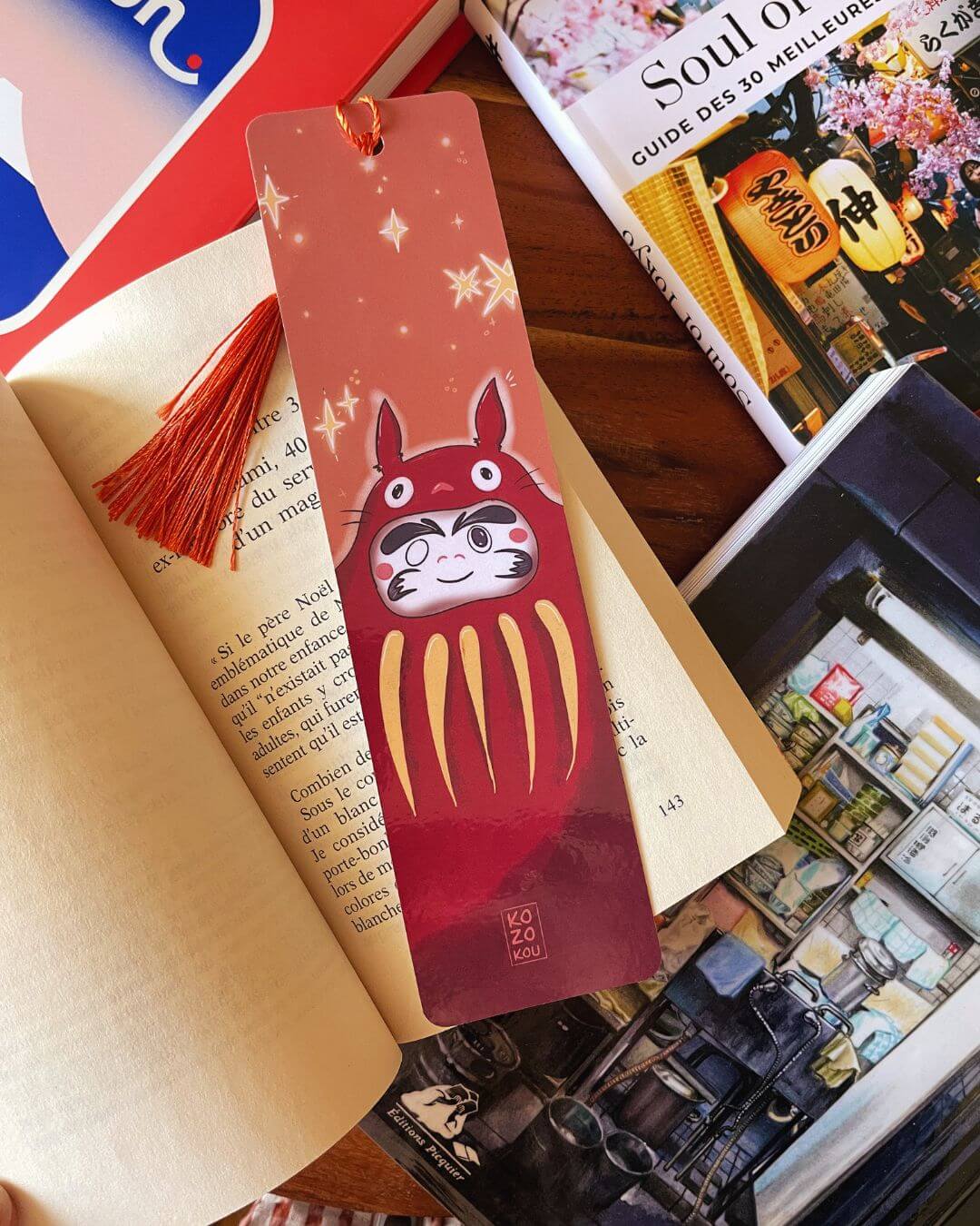 marque-page illustré représentant un totoro deguisé en daruma, avec un pompon orange