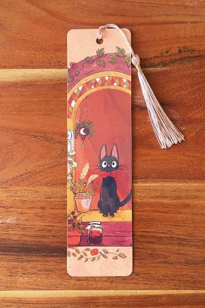 un marque-page illustré montrant le chat Jiji assis dans l'encadrement d'une fenêtre de sorcière, avec un pompon crème,
